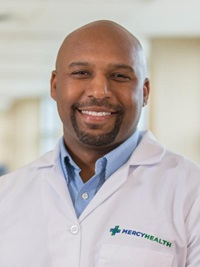 Headshot of a man in a light blue shirt wearing a Mercy Health doctor's coat.
